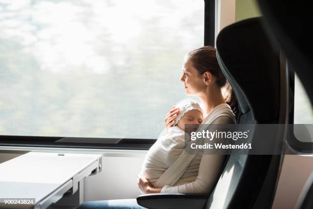 mother with baby girl traveling by train looking out of window - portabebés fotografías e imágenes de stock