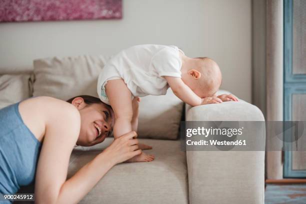 happy mother with baby girl on couch at home - windel stock-fotos und bilder