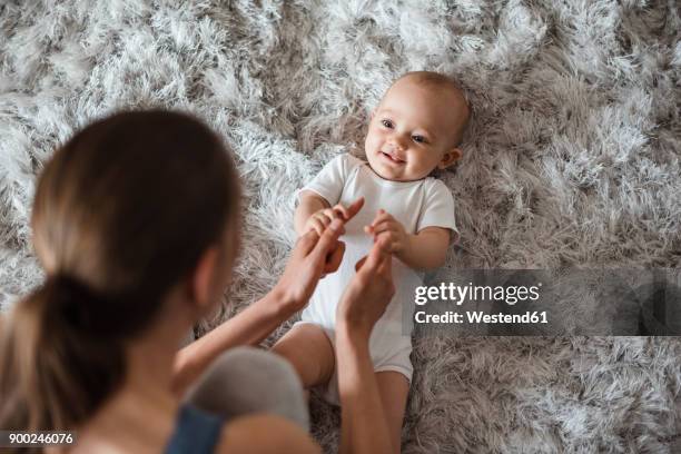 baby girl lying on carpet at home looking at mother - family with one child mother bonding family adult daughter focus on background leisure stock-fotos und bilder