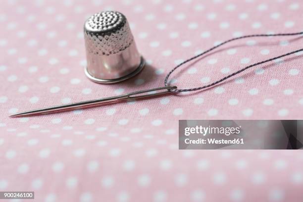 thimble, needle and thread on cloth - nähset stock-fotos und bilder