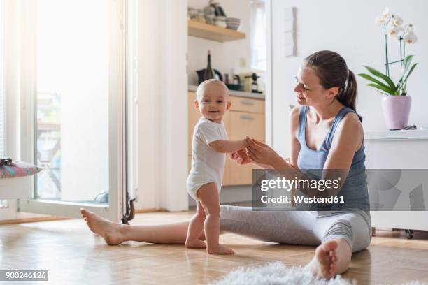 portrait of happy baby girl with mother at home - mum sitting down with baby stockfoto's en -beelden