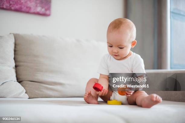 baby girl playing on couch at home - baby playing stock pictures, royalty-free photos & images