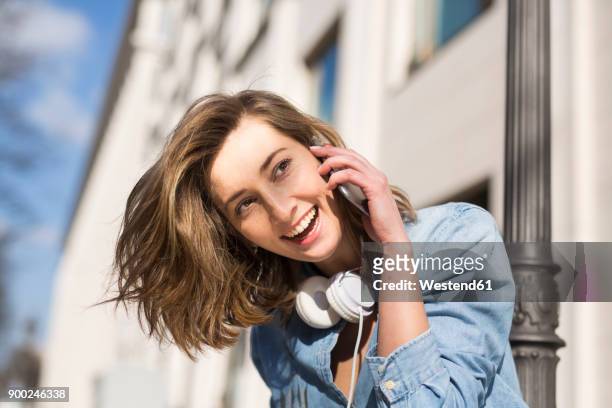 portrait of laughing woman with headphones on the phone - tête penchée photos et images de collection