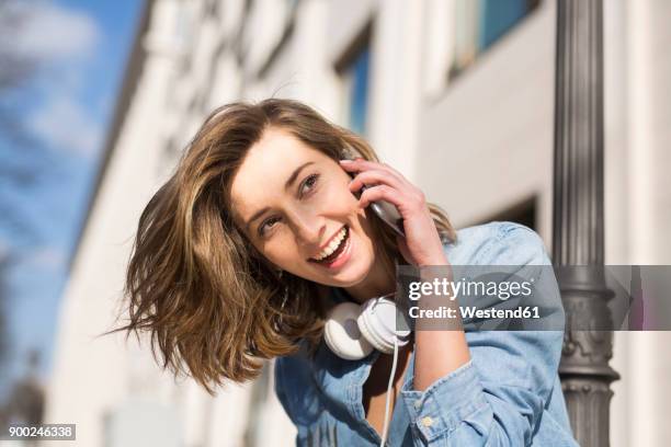 portrait of laughing woman with headphones on the phone - hoofd schuin stockfoto's en -beelden