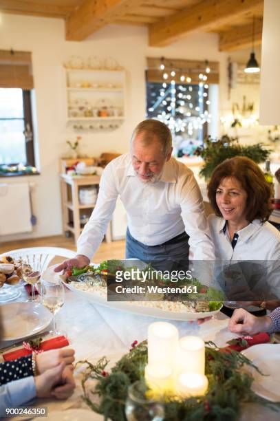 senior man serving fish for family at christmas dinner - 5 fishes stock pictures, royalty-free photos & images