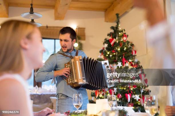 young man playing accordion at christmas dinner table - accordion instrument stockfoto's en -beelden