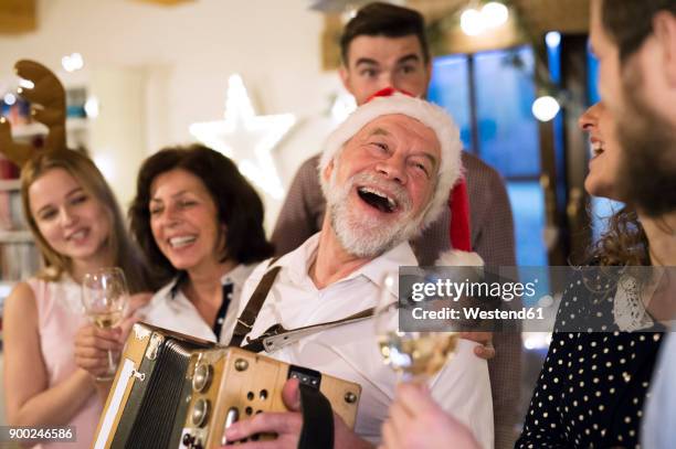 senior man playing accordion for happy family at christmas - old man woman christmas stock pictures, royalty-free photos & images