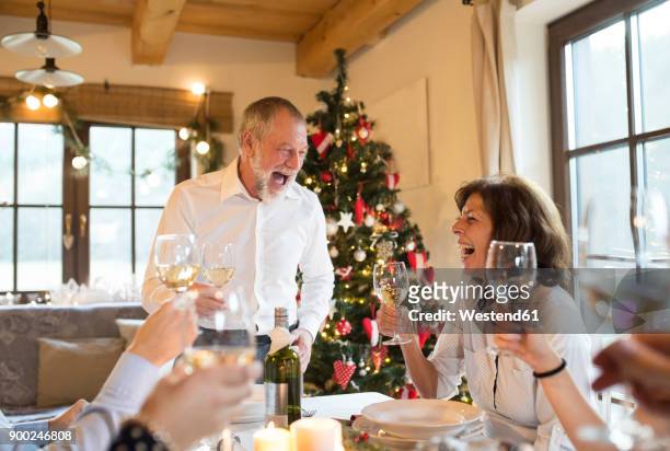 happy senior man with family having christmas dinner - old man woman christmas stockfoto's en -beelden