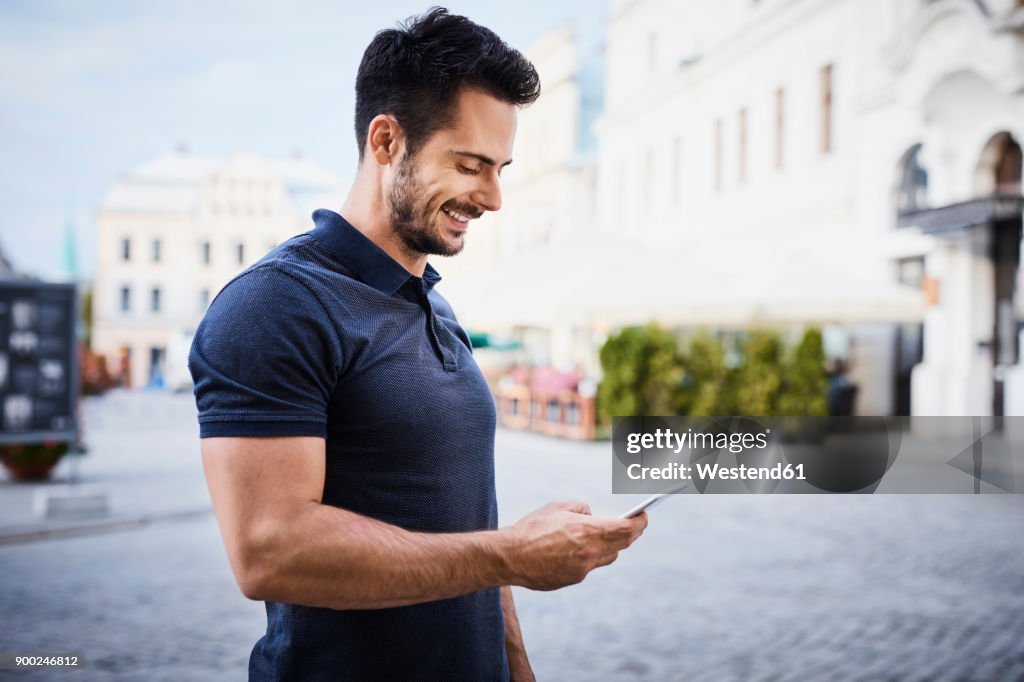 Smiling man using cell phone in the city