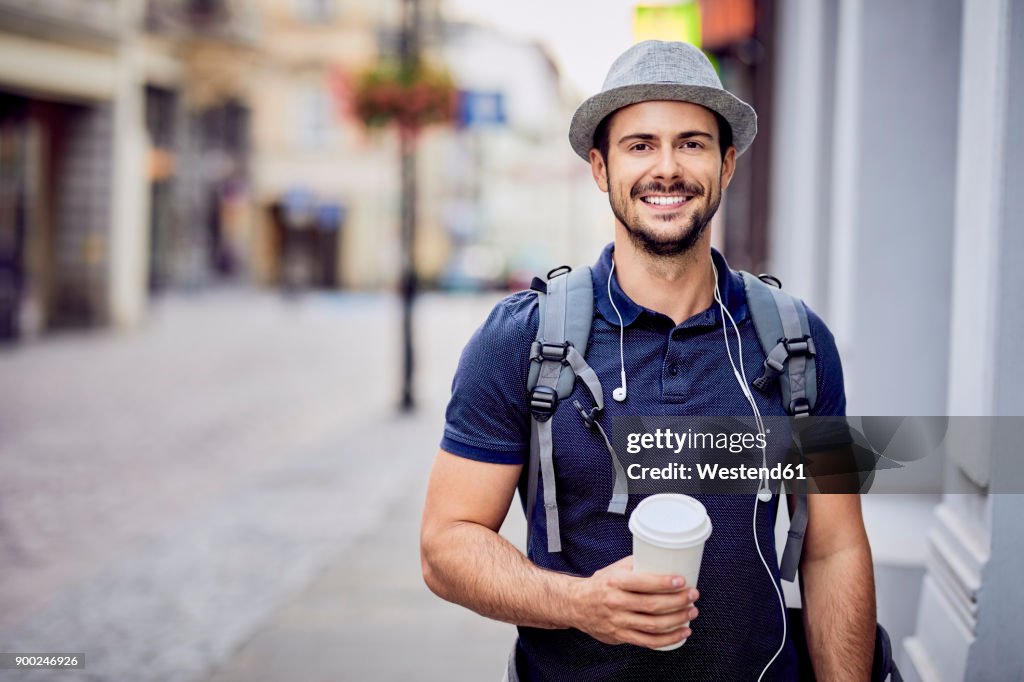 Portrait of a traveler with backpack holding coffee