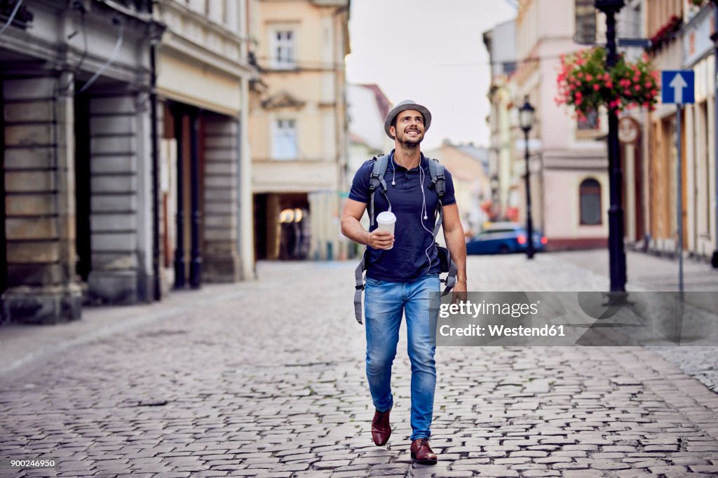 Traveler with backpack and coffee admiring the architecture