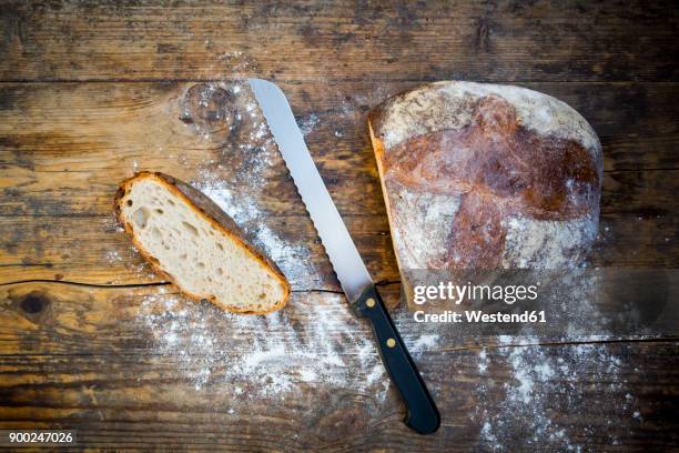 cut wheat bread powdered with flour and bread knife on dark wood - bread knife stock-fotos und bilder