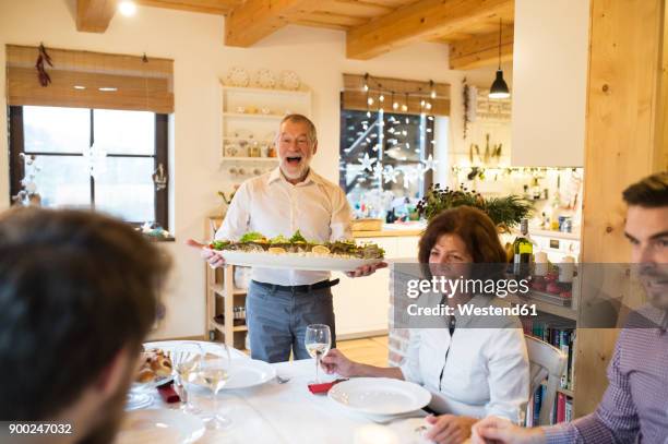 happy senior man serving fish for family at christmas dinner - serving dish imagens e fotografias de stock