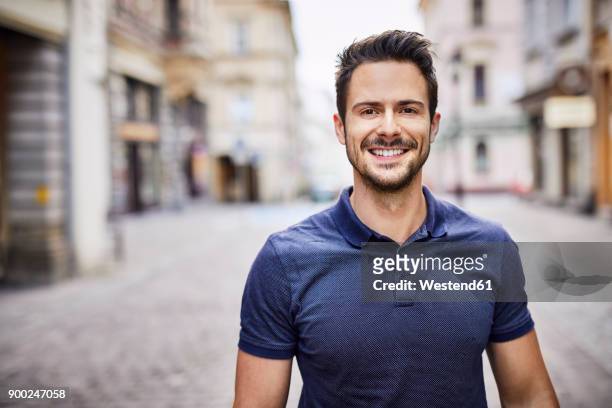 smiling man standing on city street - beard men street foto e immagini stock