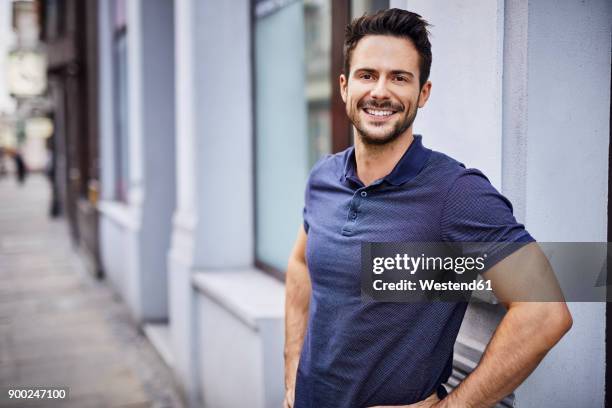 smiling man standing on city street - polo shirt stock pictures, royalty-free photos & images