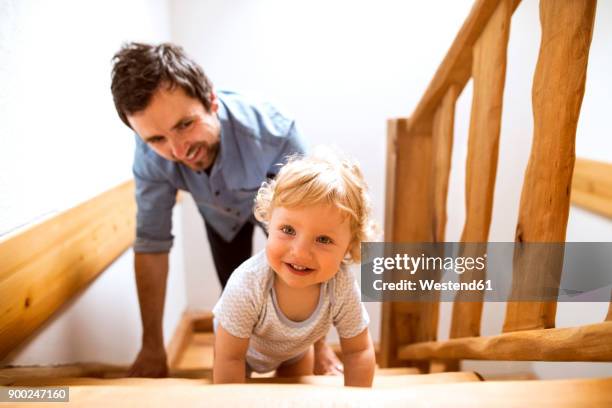 father with little boy on wooden stairs at home - baby climbing stock pictures, royalty-free photos & images
