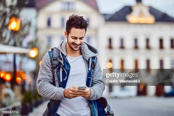 man using phone at the evening in the city - señal de información fotografías e imágenes de stock