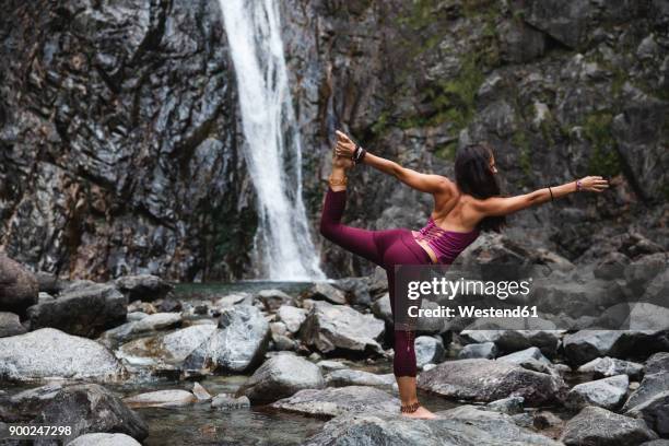 italy, lecco, woman doing lord of the dance yoga pose on a rock near a waterfall - lord of the dance pose stock pictures, royalty-free photos & images