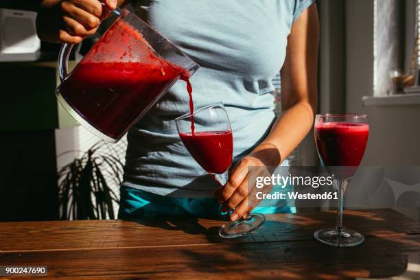 woman pouring fresh squeezed juice into glasses, partial view - woman squeezing orange stockfoto's en -beelden