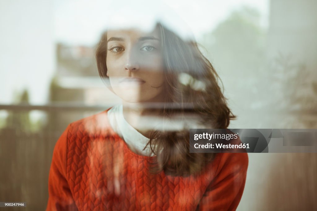 Portrait of serious young woman behind glass pane