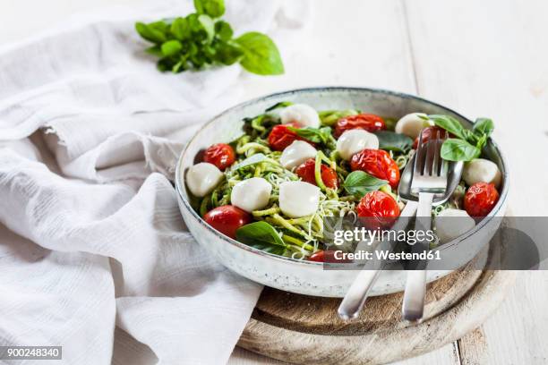 zoodles caprese, spiralized zucchini, glass noodles, pesto, plum tomatoe, mozarella balls - cheese salad stock-fotos und bilder