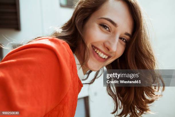 portrait of smiling young woman on balcony - brown hair stock-fotos und bilder