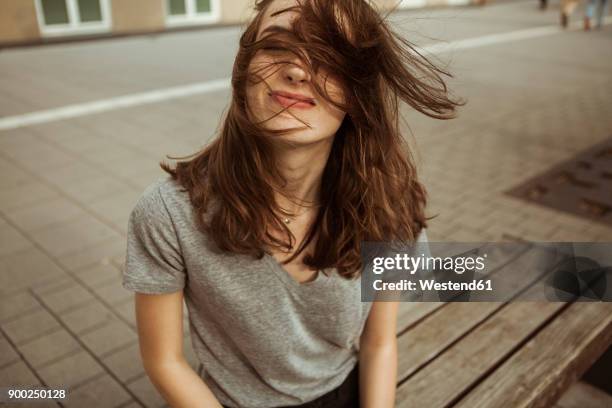 young woman outdoors with windswept hair - hair blowing stockfoto's en -beelden