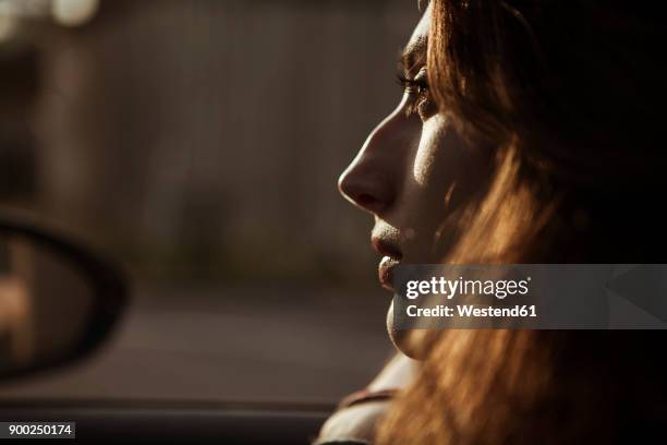 serious young woman in car - side view mirror stockfoto's en -beelden