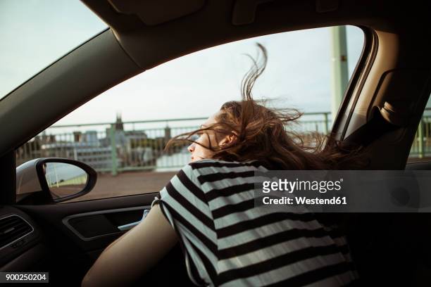 young woman leaning out of car window - car top view photos et images de collection