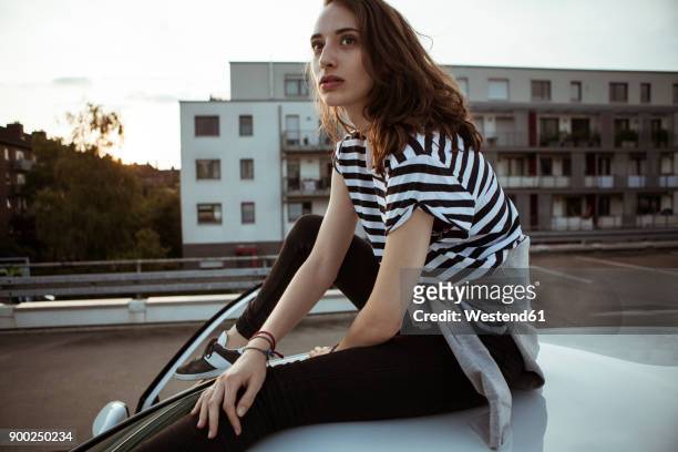 serious young woman sitting on car roof - sitting in car stock pictures, royalty-free photos & images