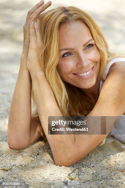 portrait of happy strawberry blonde woman lying on the beach - une seule femme d'âge mûr photos et images de collection