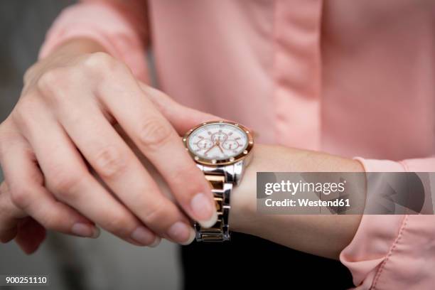 portrait of a young businesswoman looking on her wristwatch - wrist watch stock-fotos und bilder