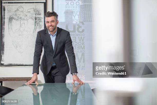 portrait of confident businessman in office - leaning ストックフォトと画像