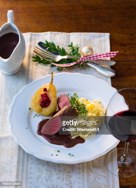 plate of venison filet with ribbon noodles, stuffed pear and red wine sauce - wildbret stock-fotos und bilder
