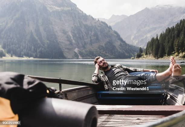 austria, tyrol, alps, relaxed man in boat on mountain lake - freizeitaktivität stock-fotos und bilder