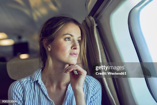 serious woman looking out of airplane window - flugpassagier stock-fotos und bilder