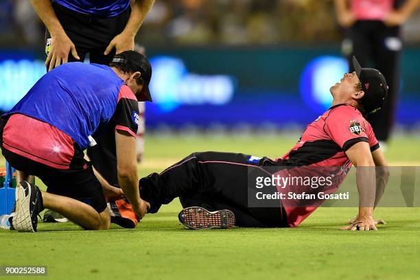 Stephen O'Keefe of the Sixers is assisted by trainers after sustaining an injury during the Big Bash League match between the Perth Scorchers and the...