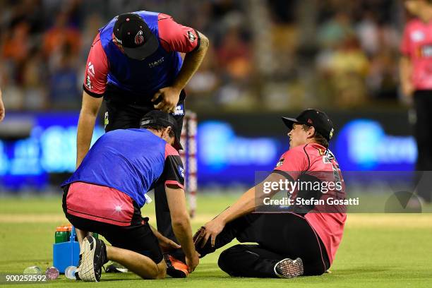 Stephen O'Keefe of the Sixers is assisted by trainers after sustaining an injury during the Big Bash League match between the Perth Scorchers and the...