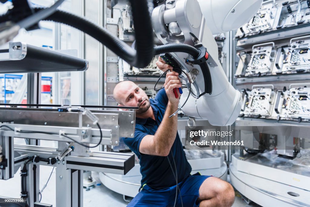 Man working at industrial robot in modern factory