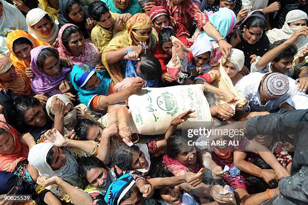 Pakistani women gather to buy bags of wheat flour on control rates at the Ramadan Bazaar in Lahore on August 23, 2009 on the first day of the Muslim...