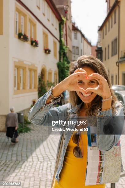 germany, rothenburg ob der tauber, portrait of happy woman shaping heart with her fingers - rothenburg stock pictures, royalty-free photos & images