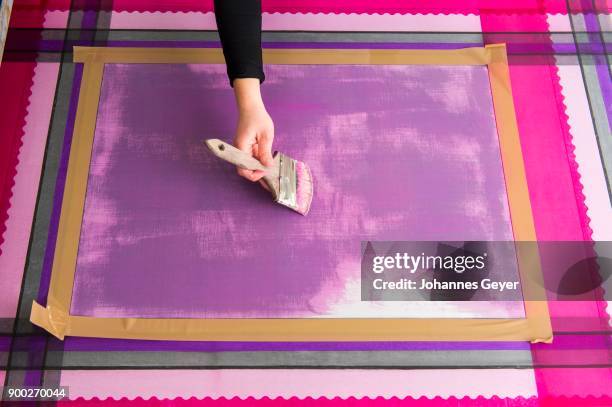 block printing, hand with brush coating taped surface with paint, on taut and printed fabric, bad aussee, styria, austria - bad aussee stock pictures, royalty-free photos & images