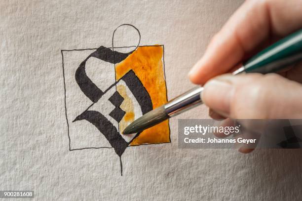 calligraphy studio, hand paints surface with brush, letter s on torchon paper, seebruck, upper bavaria, germany - torchon stock-fotos und bilder