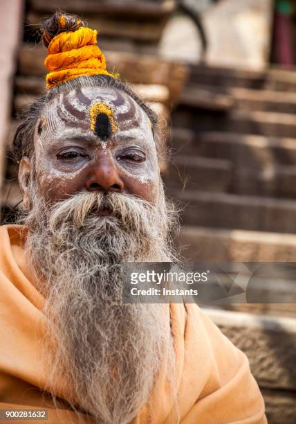 in varanasi, head shot of a sadhu sitting in one of the ghat' stairs. - sadhu stock pictures, royalty-free photos & images