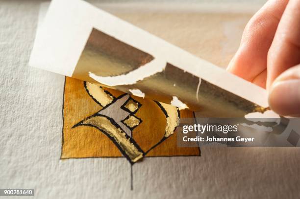 calligraphy studio, hand removing sheet of transfer gold, letters s coated with gold on torchon paper at back, seebruck, upper bavaria, germany - torchon bildbanksfoton och bilder