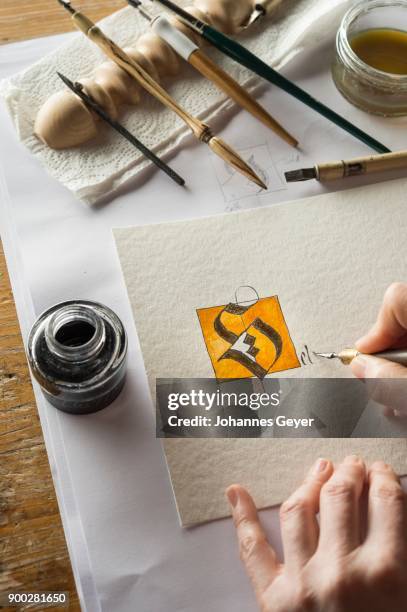 calligraphy studio, hand writing text with pen and nib, letter s coated with gold on torchon paper, inkwell and pen holder at back, seebruck, upper bavaria, germany - torchon bildbanksfoton och bilder