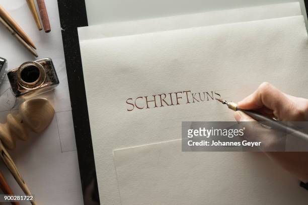 calligraphy studio, hand writes text with ink, pen and nib, roman capitalis writing on ingres paper, inkwells and pen holder at back, seebruck, upper bavaria, germany - ingres stock pictures, royalty-free photos & images