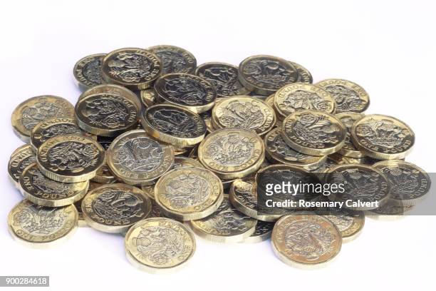 newly minted one pound coins in heap, on white. - one pound coin stock pictures, royalty-free photos & images