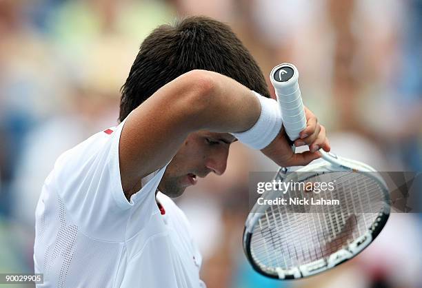 Novak Djokovic of Serbia wipes sweat from his face against Roger Federer of Switzerland in the Singles Final during day seven of the Western &...