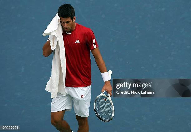 Novak Djokovic of Serbia wipes sweat from his face against Roger Federer of Switzerland in the Singles Final during day seven of the Western &...